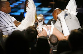 Sacha Baron Cohen, wearing a jockstrap and wings, lands on Eminem's head at an MTV award show.