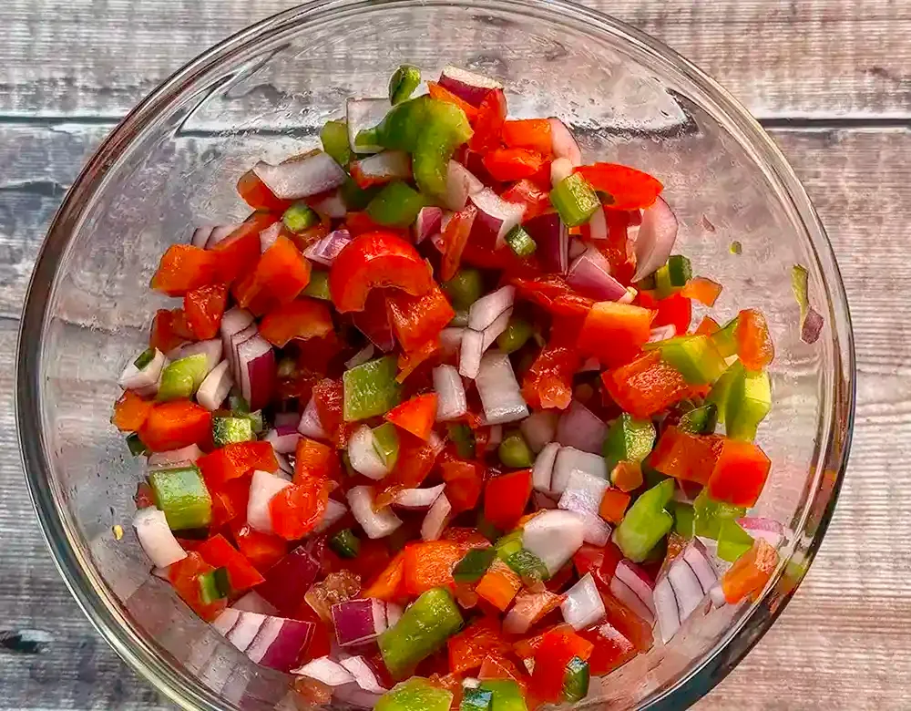 Chopped tomatoes, onions, peppers and chilli pictured in a bowl.