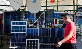 Solar panels are sold alongside food in a market in Burkina Faso. (Photograph Credit: Joerg Boethling/Alamy) Click to Enlarge.