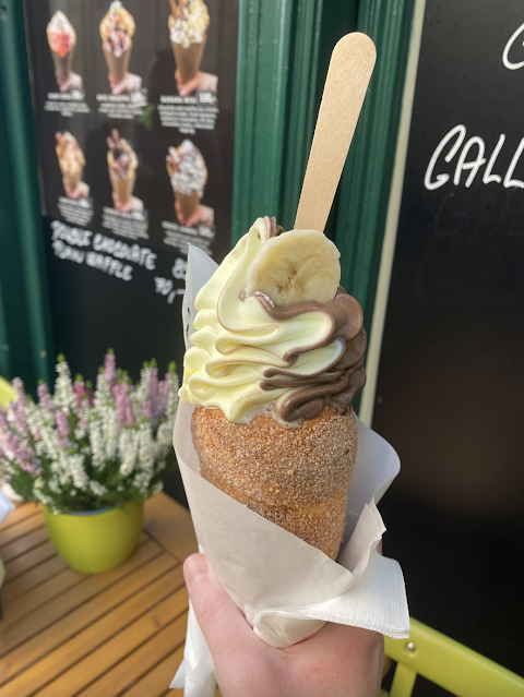 Gelato and fruit inside a trdlo which is a Czech dessert made with dough, sugar and nuts.