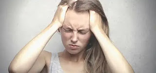 A young woman puts her hands on her head, feels a Headaches