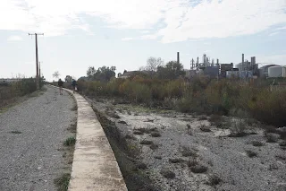 2 hikers walk on a road on the side of the river