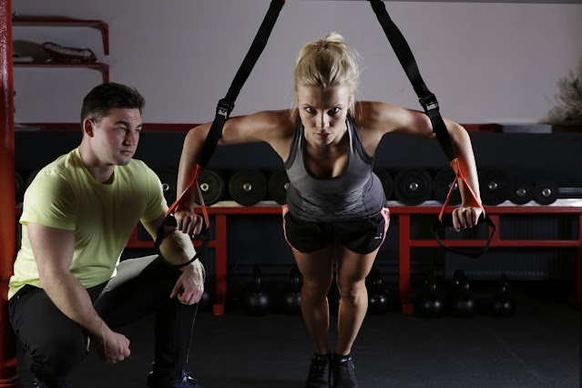 A personal trainer helping a girl workout.