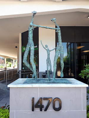 Bronze sculpture consisting of 3 figures, on top of a pedestal