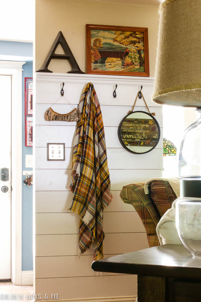 DIY planked wall with shelf and hooks in family room with plaid scarf as fall decor - www.goldenboysandme.com