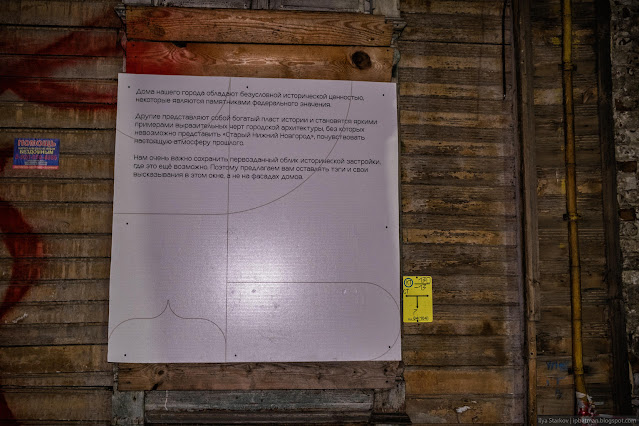 Информационный плакат в оконном проеме деревянного дома