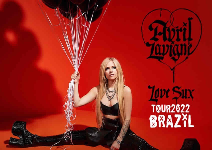 Imagem de fundo laranja mostra a Avril Lavigne sentada vestida com uma roupa totalmente preta segurando alguns balões.