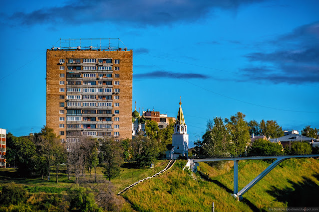 Красный многоэтажный дом, церковь и пешеходный мостик