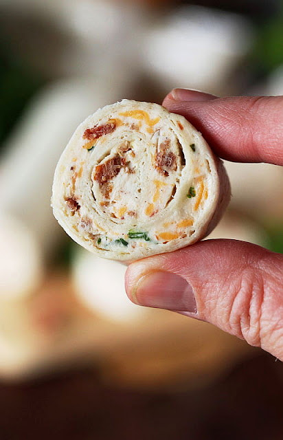 Close-Up of a Bacon-Cheddar Ranch Roll-Up Showing Bacon Pieces and Shredded Cheddar in Filling Image