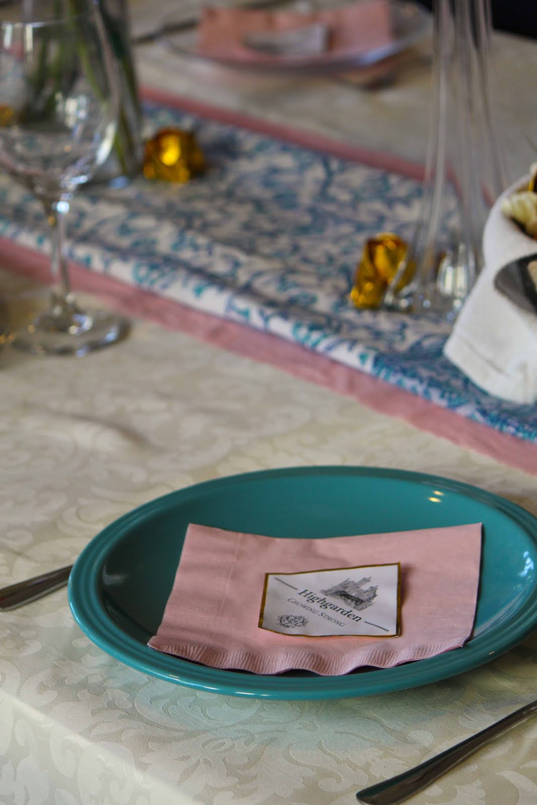 Place setting: turquoise plates, with white and gold menus and pink napkins