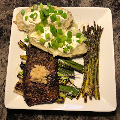 Prime ribcap grilled rare on a bed of leeks with grilled asparagus and baked potato