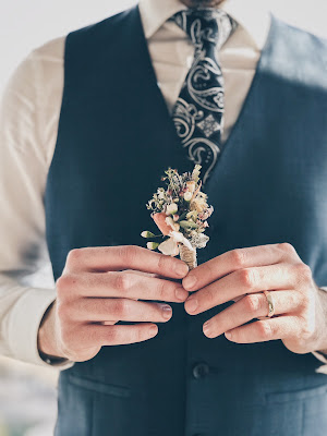 Novio con camisa, chaleco y boutonniere en la mano