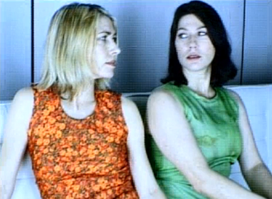 Sonic Youth's Kim Gordon in a beautiful 90's shiny orange dress with Kim Deal of The Pixies and The Breeders in a green dress. Still / screenshot from Little Trouble Girl (1995)