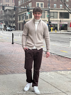 Marshall wearing a cardigan, turtleneck and brown corduroy pants
