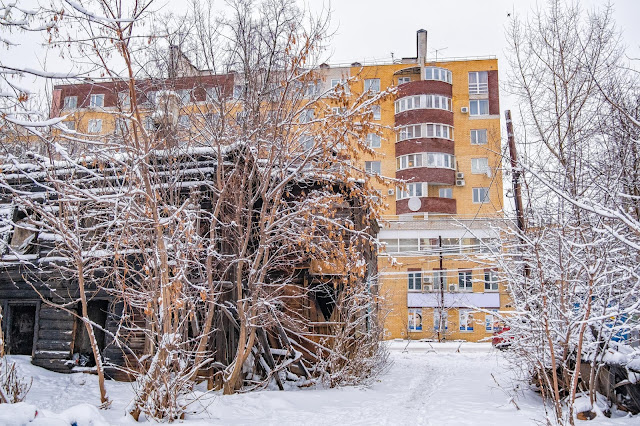 Сгоревший деревянный дом на фоне новостройки