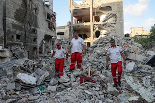 Rescue workers walk on rubbles of a destroyed building in Palestine