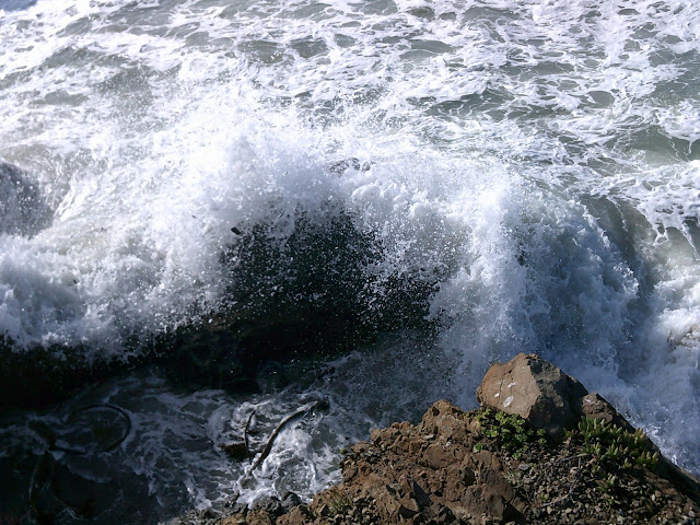 water splashing on a boulder in the ocean