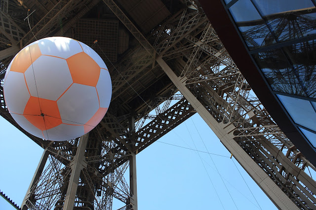 Giant soccer ball hanging from the Eiffel Tower.