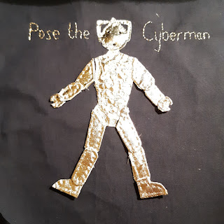 Cyberman sewn together with the caption "Pose the Cyberman"