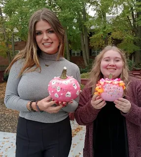 two women holding decorated pumpkins