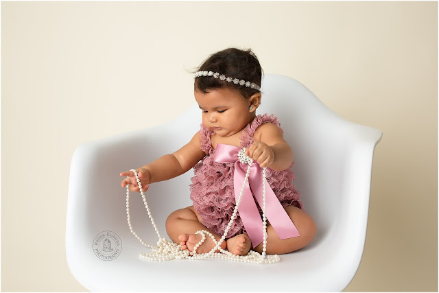 Beautiful 6-month baby girl playing with pearls