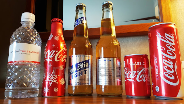 bottles in a row - bottled water of swissotel the stamford, bottle of coke, 2 bottles of San Miguel Light Beer, 2 coke-in cans