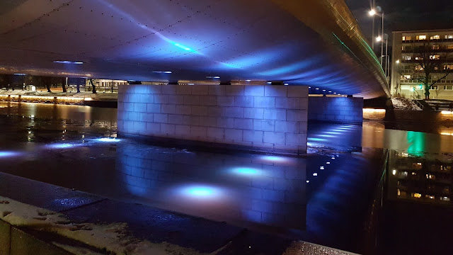 Mill Bridge and icy water, illuminated blue. 