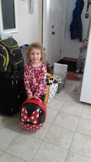 Ellie stands in front of our luggage, proudly showing the suitcase she packed