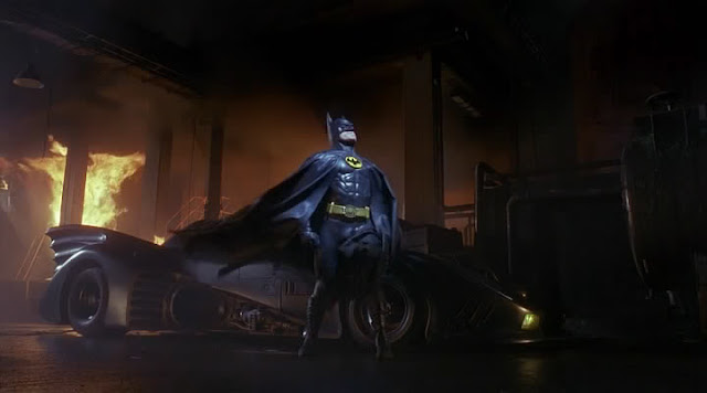 Batman strikes a pose as a building burns down behind him. Seven lives were lost that night.