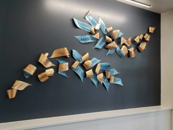 light blue and tan curled paper and metal horizontal wall sculpture with katagami handcarving