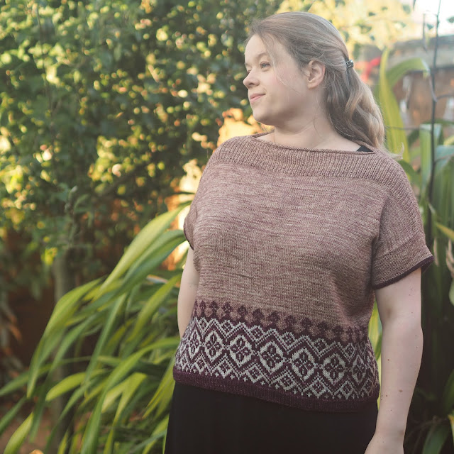 wearing Navelli top in coffee, burgundy and cream stood in front of plants