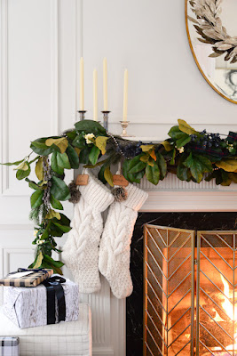 magnolia garland on fireplace mantel with candlestick holders and cable knit stockings