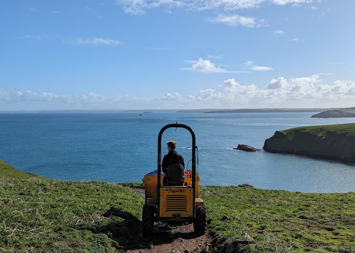 A member of staff on the dumper truck in North Haven with a calm sea in the background.