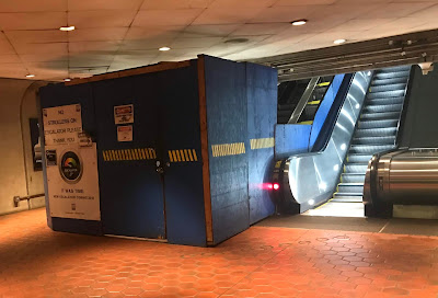Photo of the mid-level landing showing a blocked off escalator under construction and an operational escalator