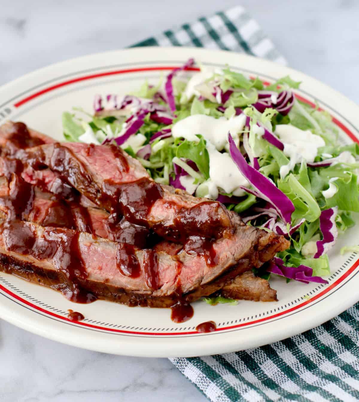 Blueberry Chipotle Grilled Flank Steak on a plate with a salad.