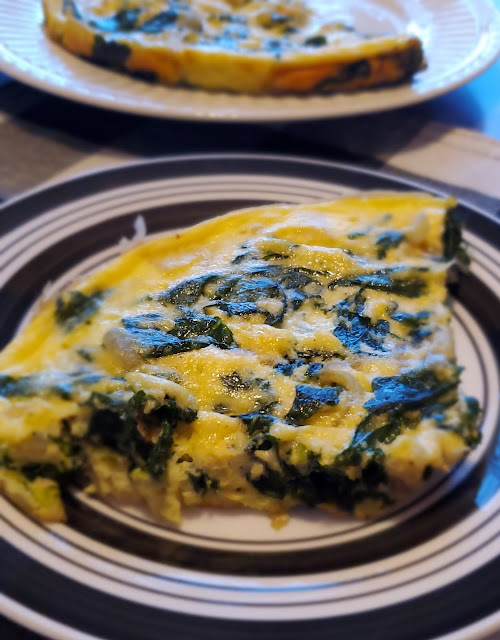 Slice of a spinach ricotta frittata on a black and white plate