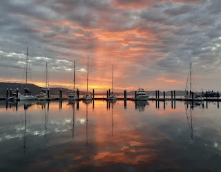 Boats and a pink and orange sunset in a marina