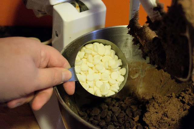 The white chocolate chips being added to the cookie dough.