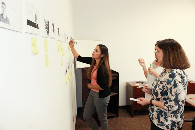 Three women using green and red markers to mark a piece of paper