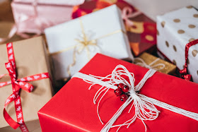 An assortment of Christmas presents wrapped in red, gold and white wrapping paper, some with ribbon in the same colours.