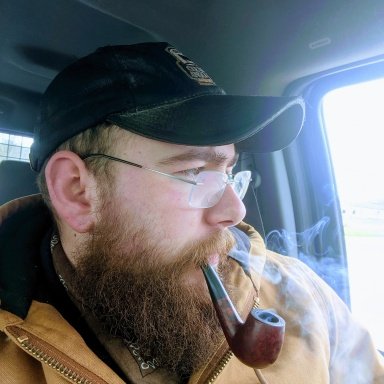 Bearded pipe sneaker driving looking out driver side window with a pipe in mouth