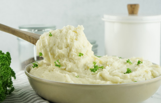 wooden spoon scooping mashed potatoes from the bowl.
