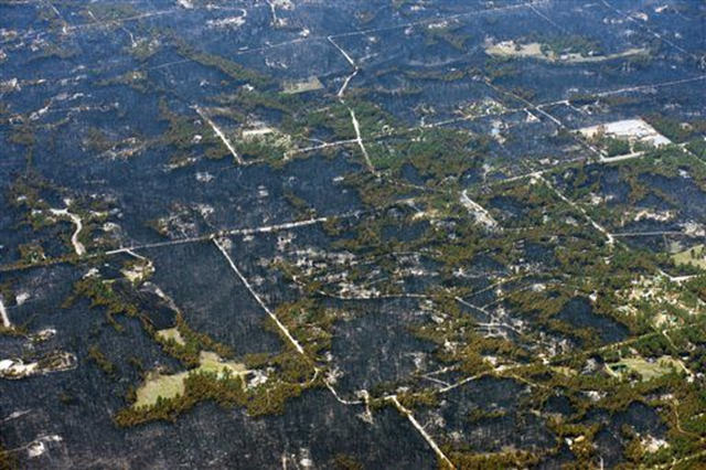 Aerial view of blackened areas that define the path of a wildfire that destroyed some homes and left others untouched in one neighborhood in the densely wooded Black Forest area northeast of Colorado Springs, Colorado, 13 June 2013. Photo: John Wark / AP Photo 