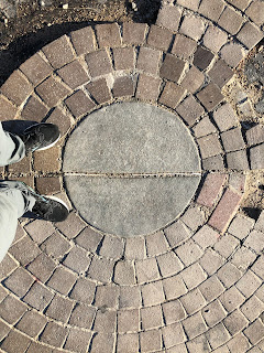 feet next to a concrete and brick marker