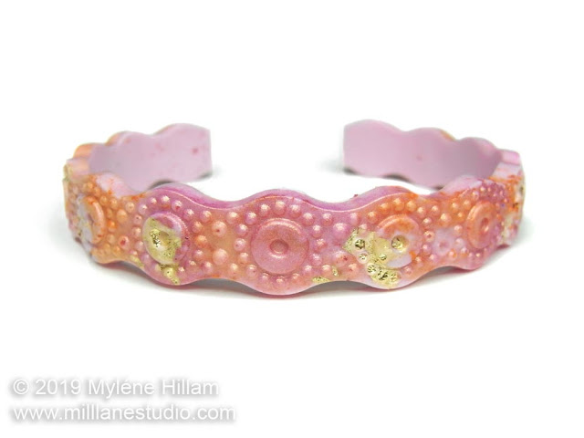 Pink and orange wavy resin bracelet with gold leaf flecks throughout.