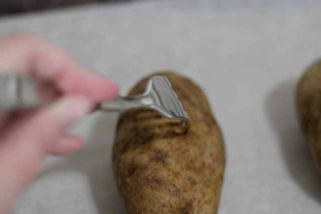 Holes being poked into the potato with a fork. 