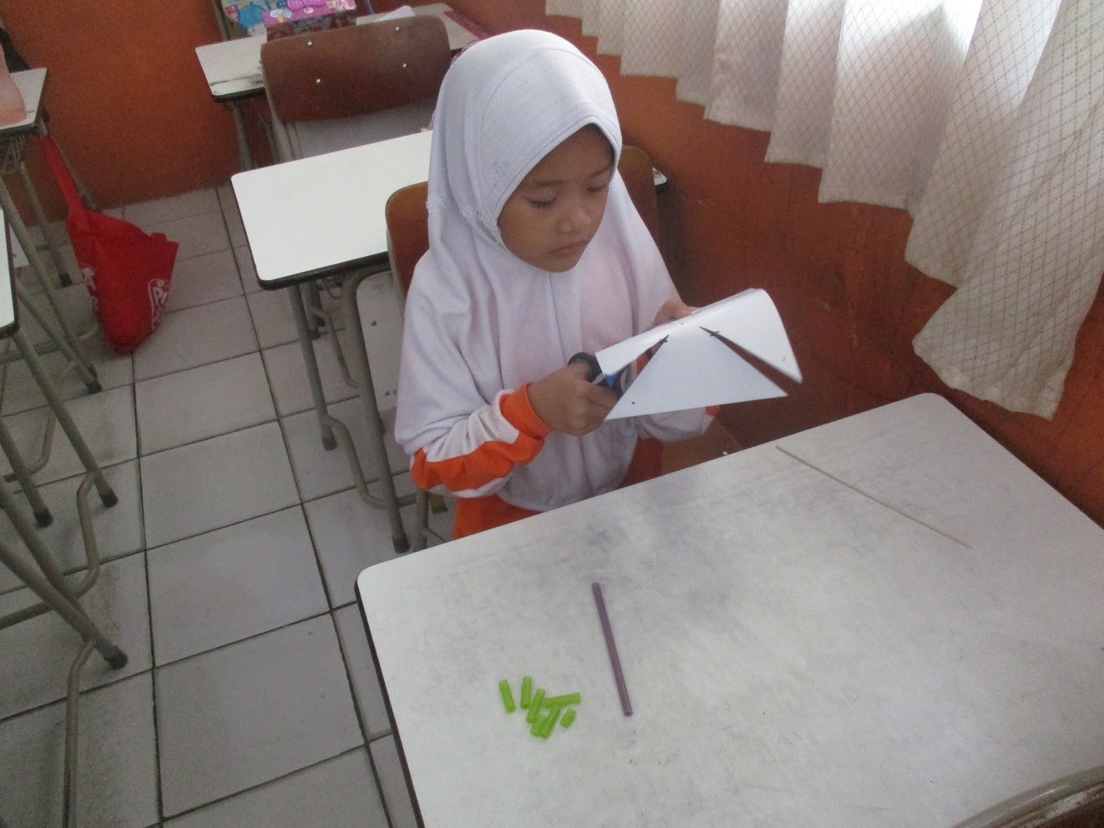 Salah satu siswi kelas 1 sedang memotong kertas untuk di jadikan kincir angin