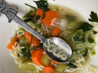 alphabet soup with carrots and celery and the word "soup" in noodles on the spoon