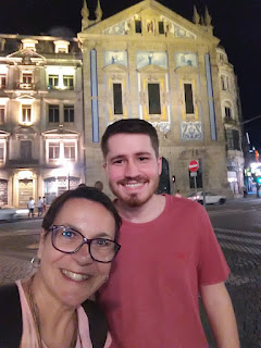 homem e mulher posando em frene à uma igreja de azulejos à noite