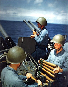 USS Alaska (CB-1): Crew of a 40mm quad antiaircraft machine gun mount loading clips into the loaders of the left pair of guns. Taken on 6 March 1945, during the Iwo Jima operation. The man at the right is Seaman Second Class Richard Roberts, and the gun captain (in the phone talker's helmet) is Gunner's Mate Second Class Glenn F. Groff.